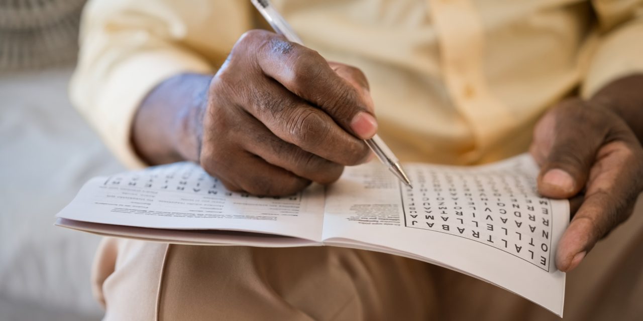Person writing in word puzzle book